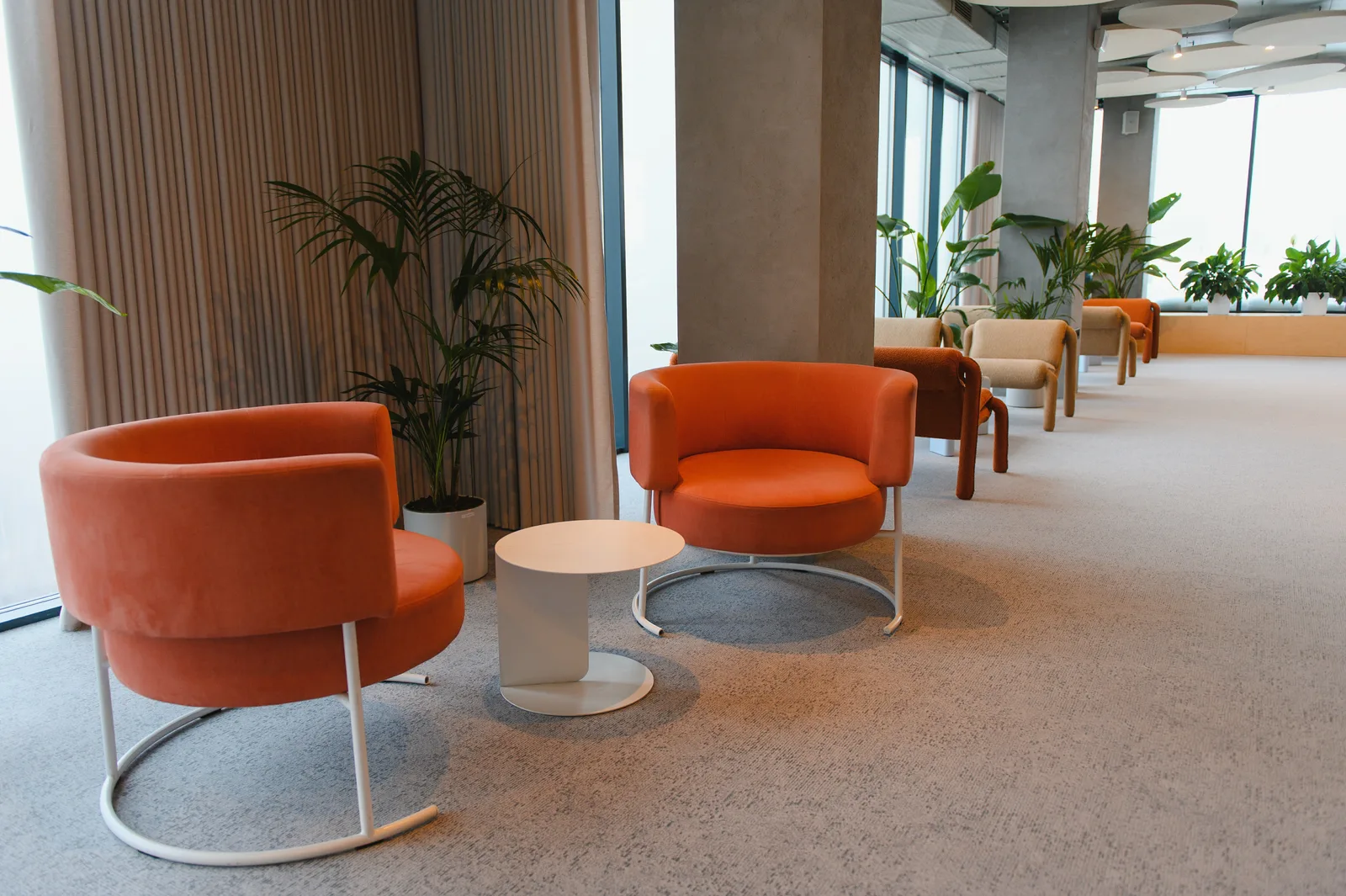 A waiting area with orange armchairs by the windows
