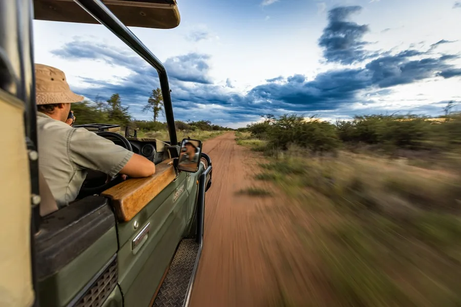 A guide driving a game vehicle down a dirt road.